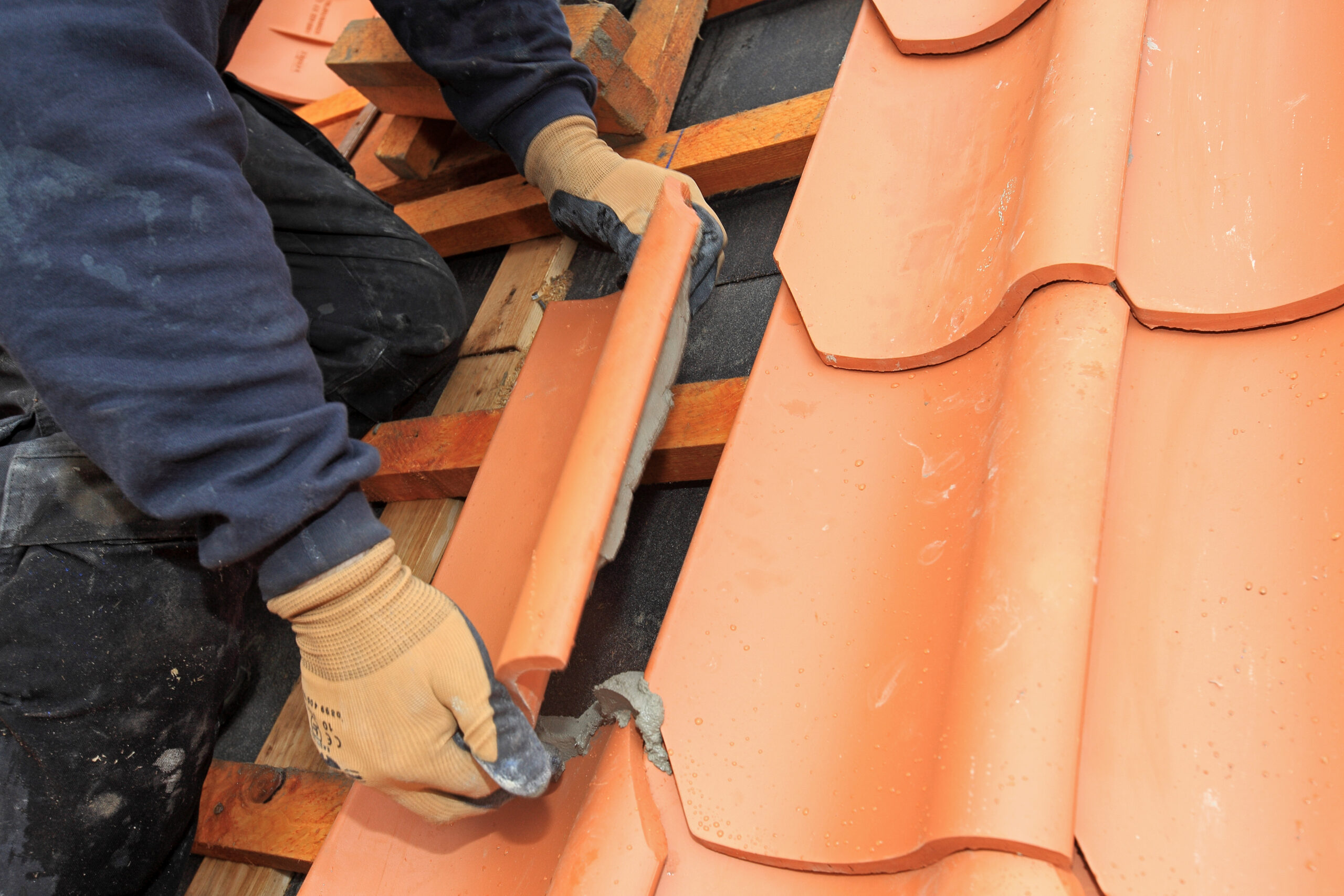 Red tile roof being installed on home