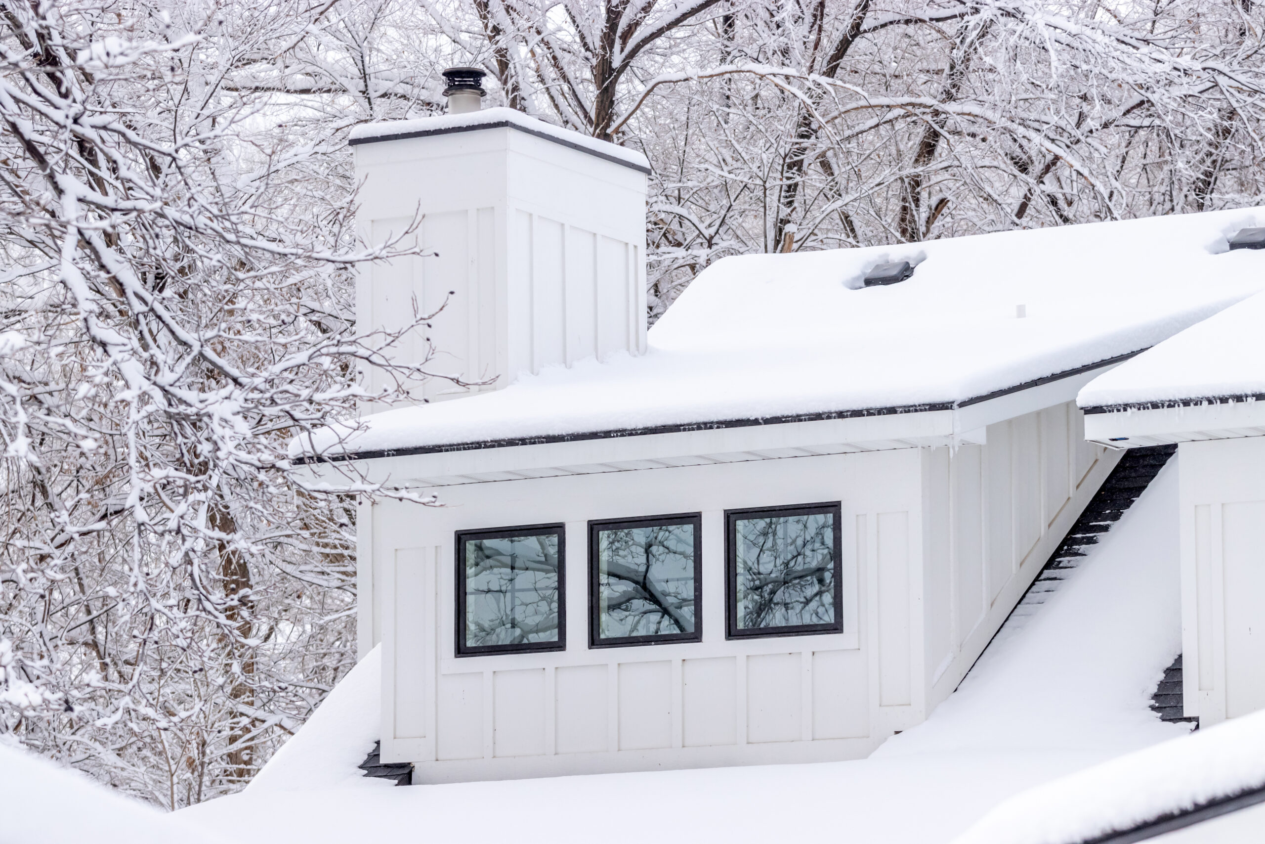 Beautiful black framed windows in white house with snow covering the ground