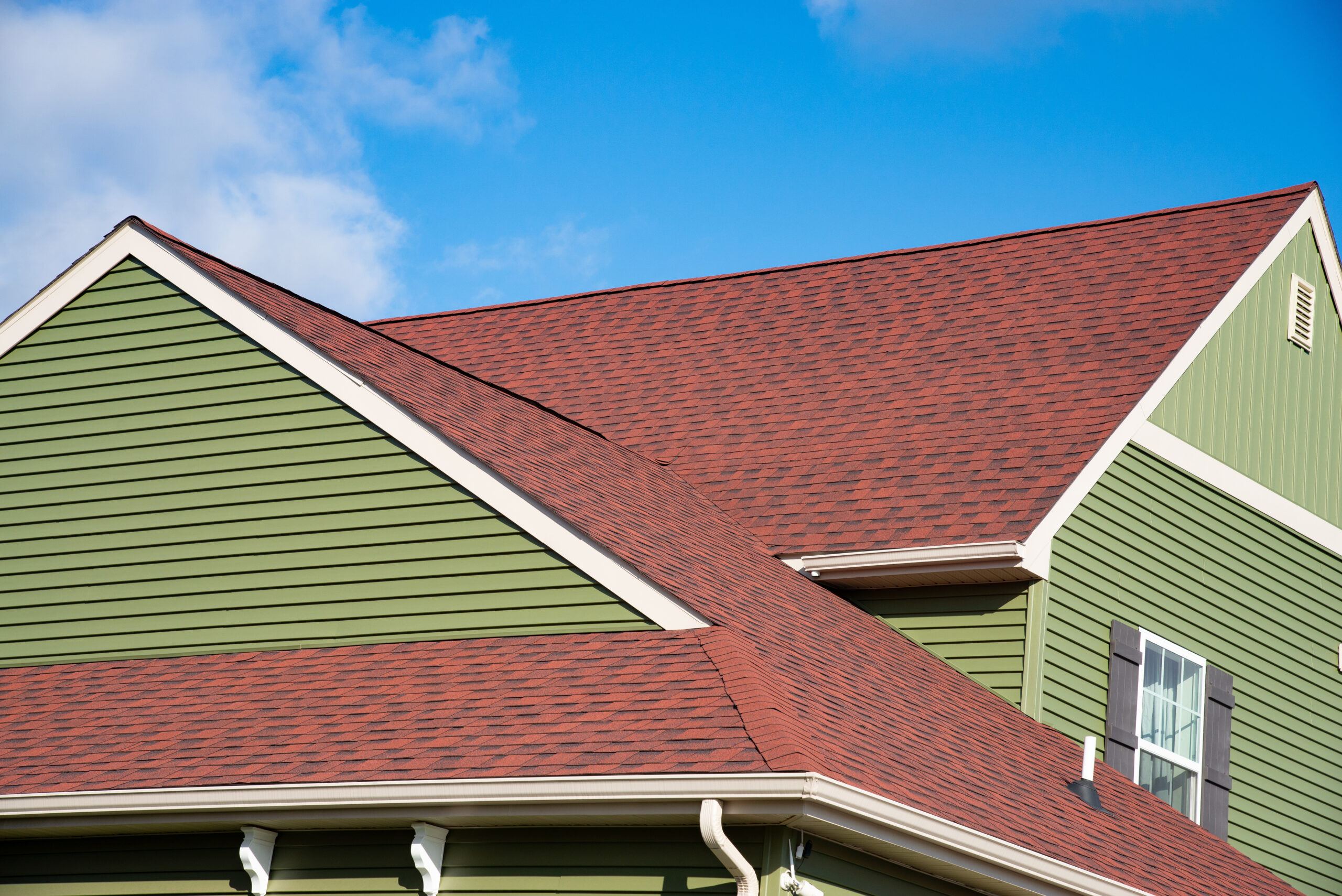 Red asphalt roof on green siding home