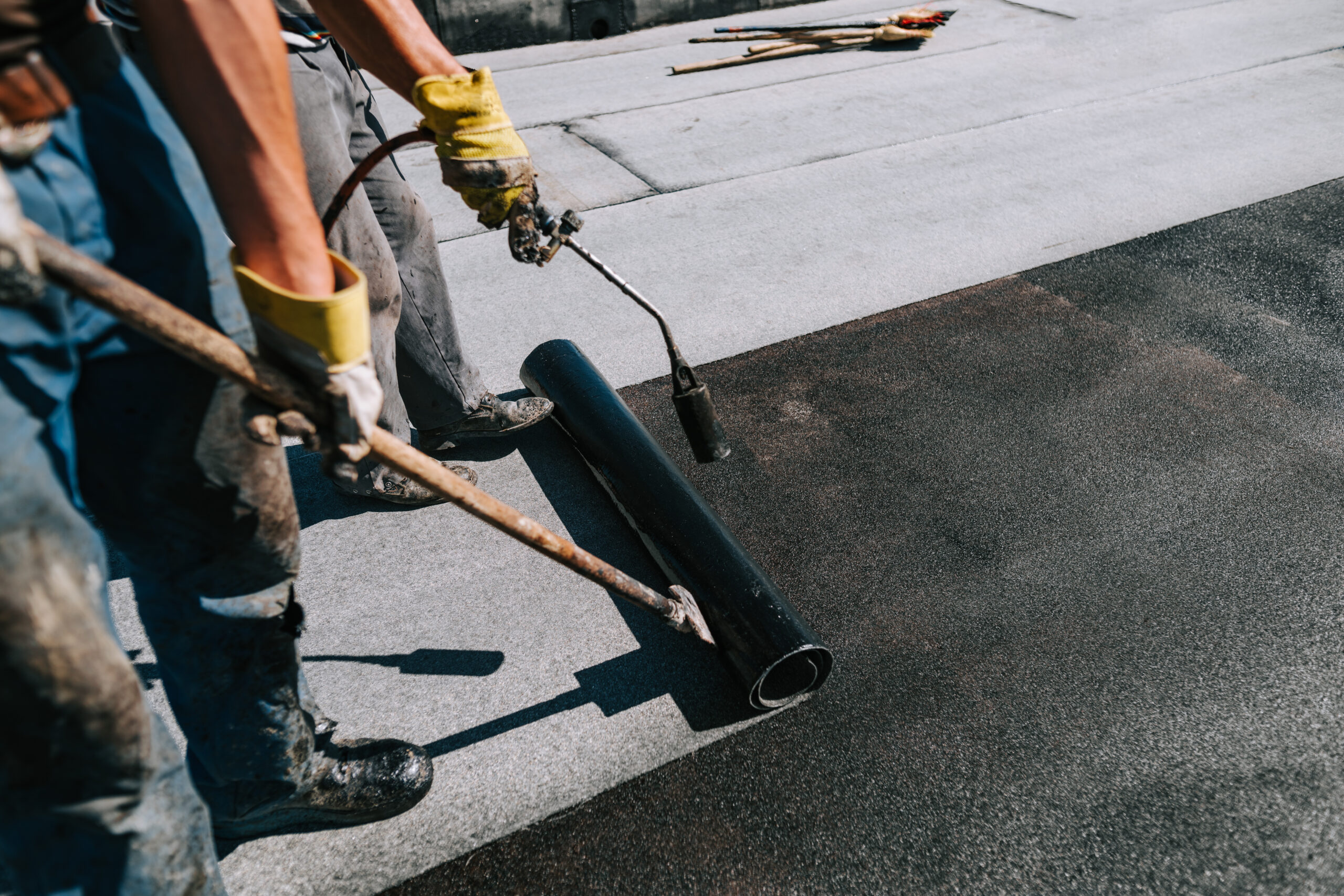 Black flat roofing being laid on building