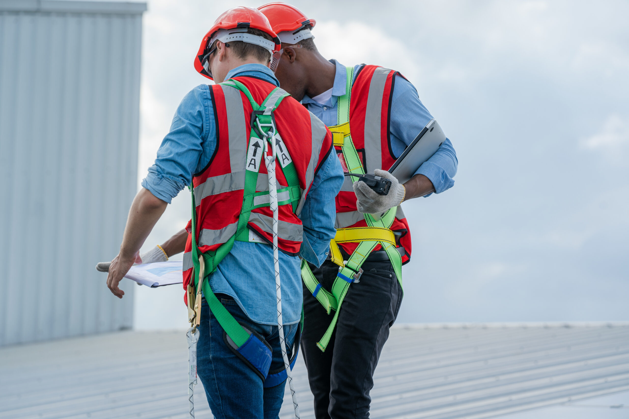 Two roofers on the commercial roof making notes while checking the condition