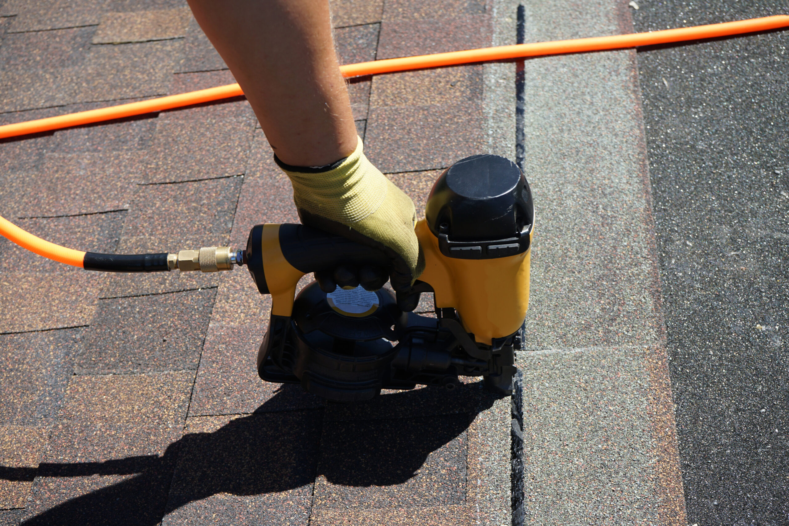 Close up view of nail gun and asphalt roof being repaired