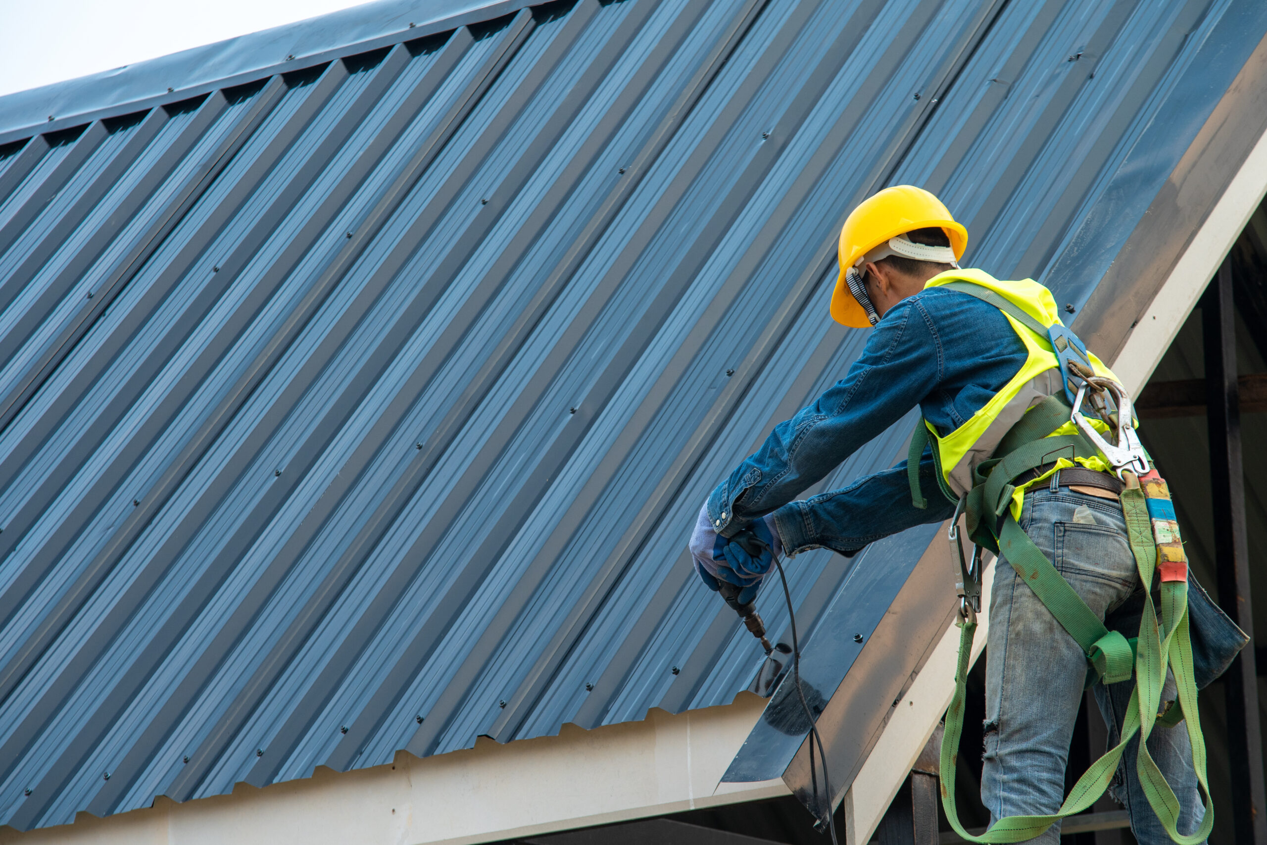 Workers installing a black metal roof on building