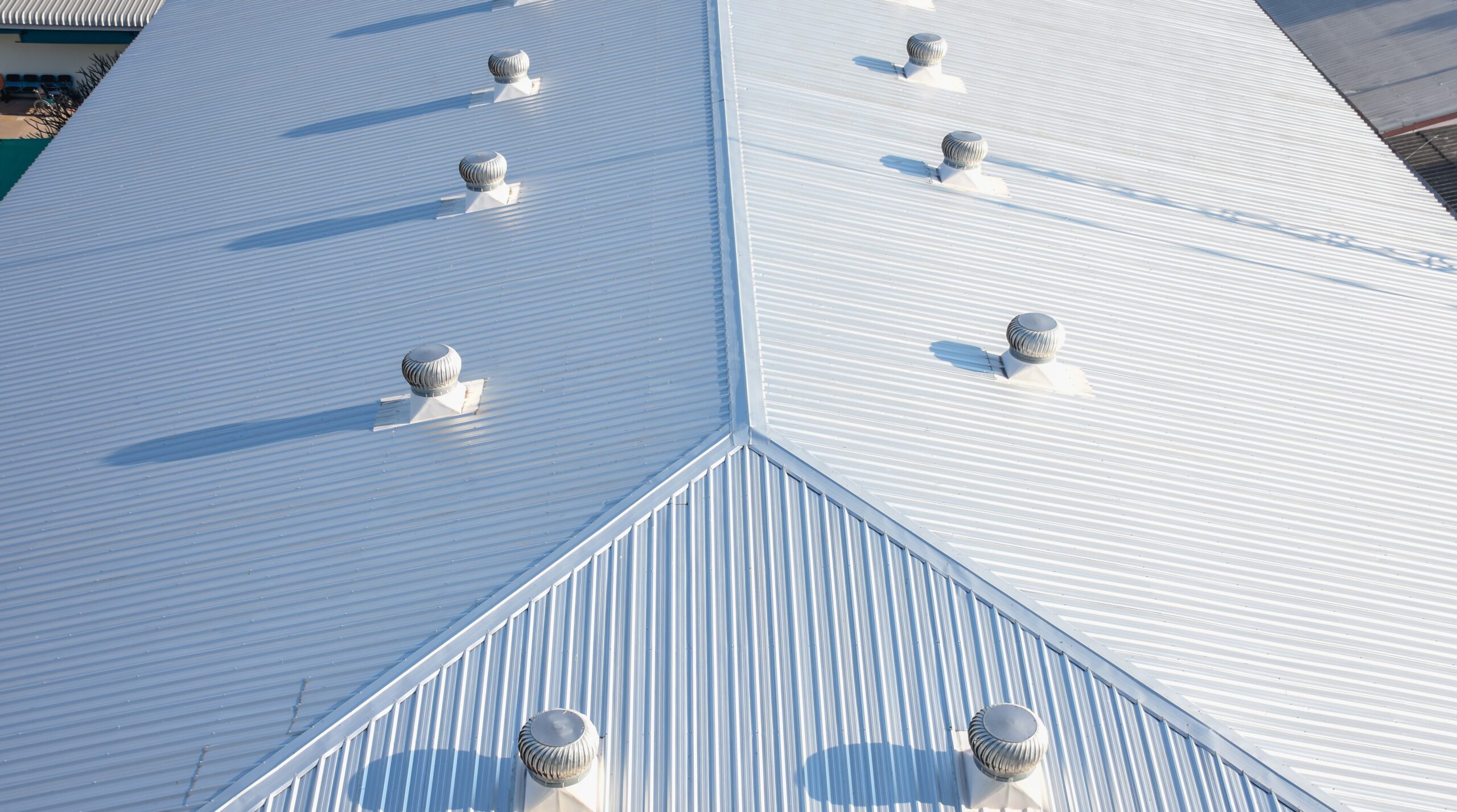 Overhead view of white metal commercial roof with lots of roof vents on it