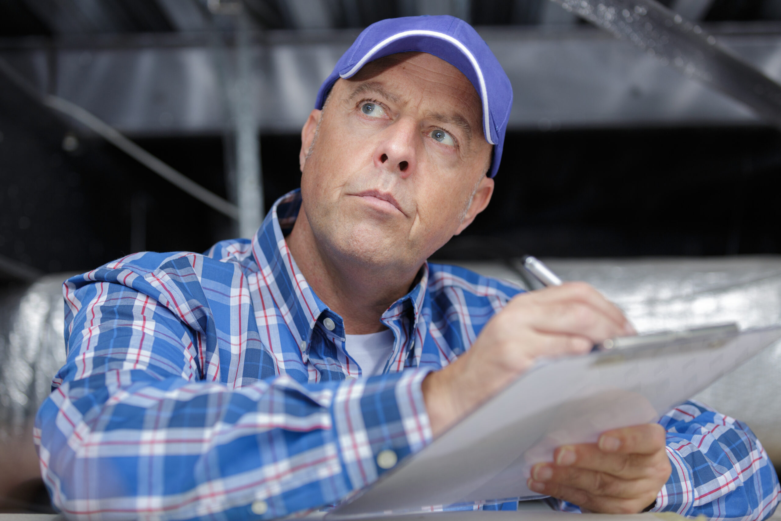 Roofer looking at roof and writing on clipboard