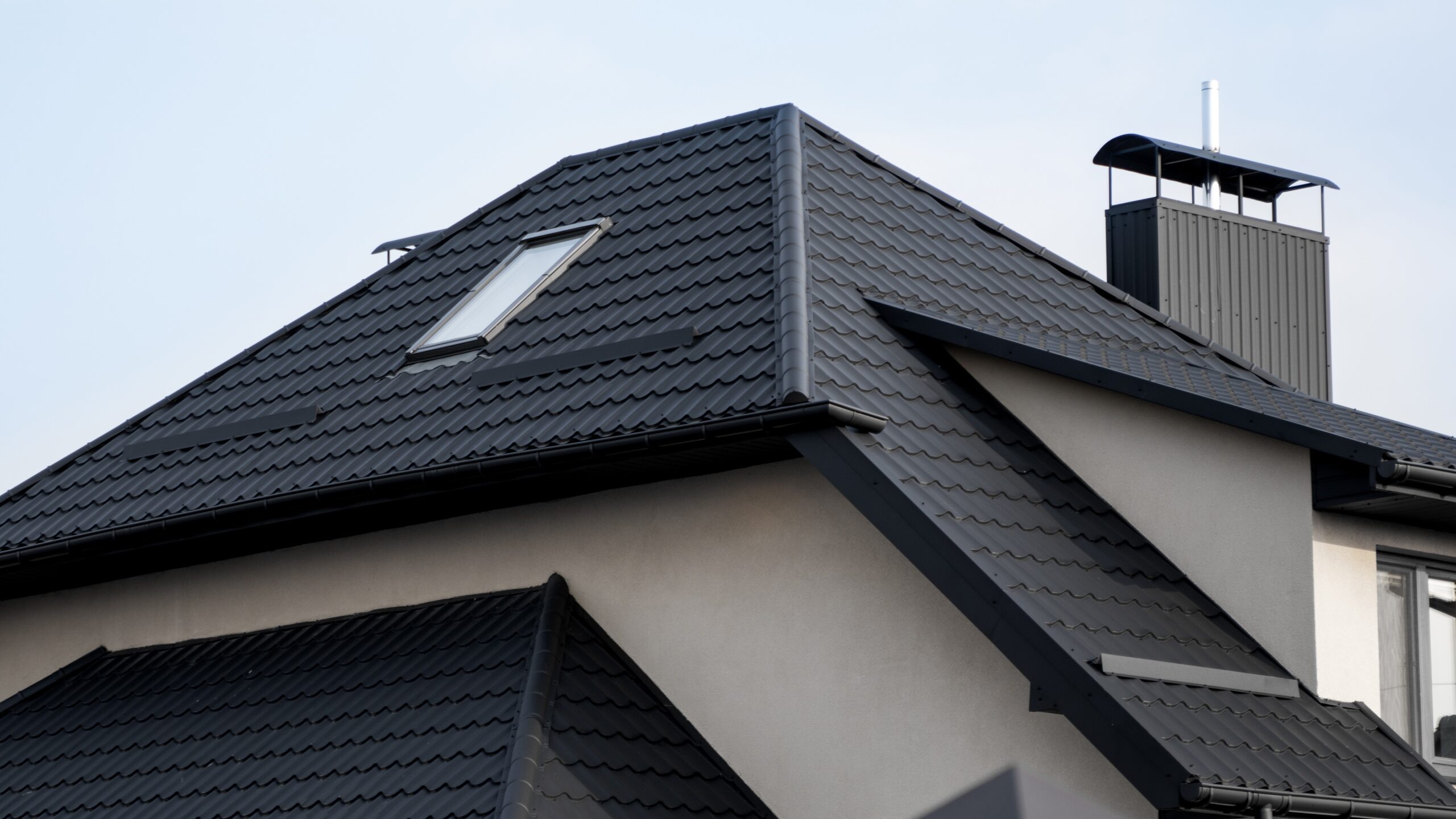 Home with black metal roofing with a skylight and white siding